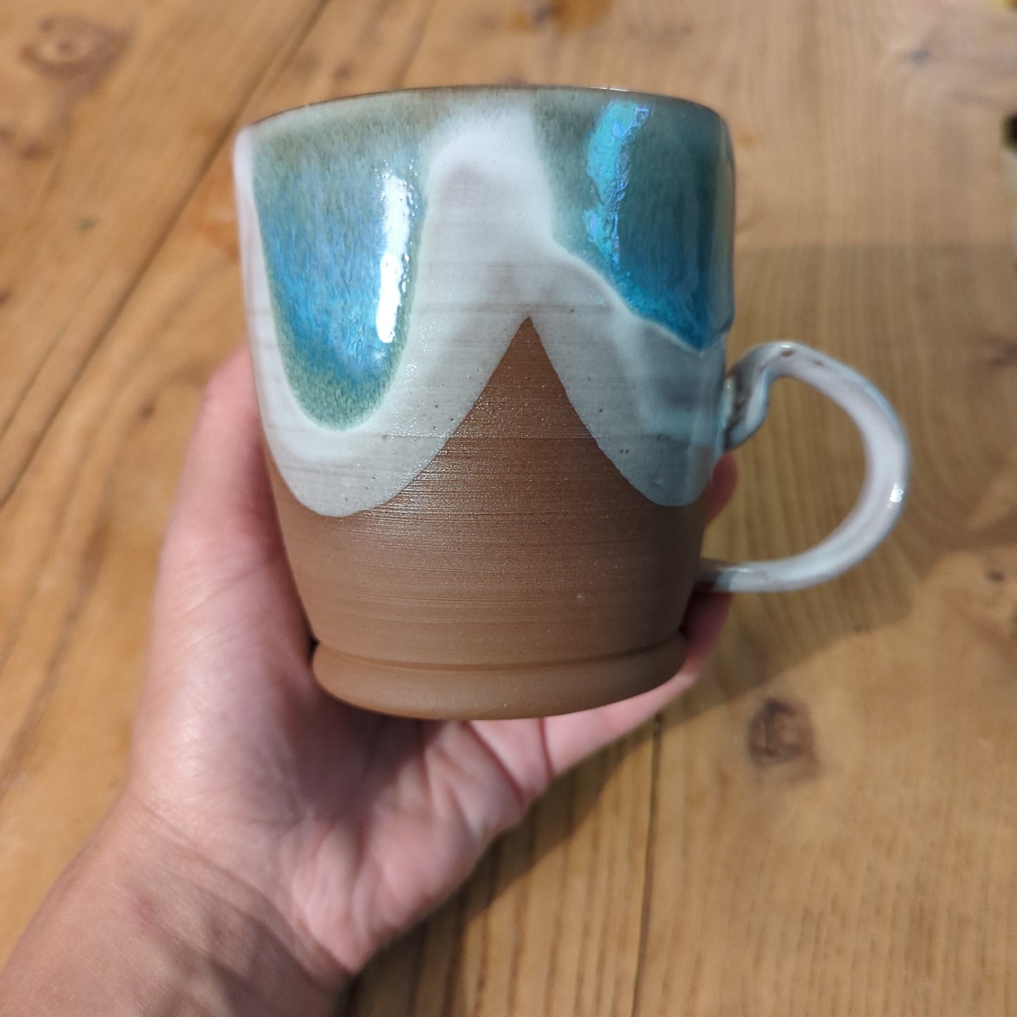 Blue and white glaze curves on red clay mug