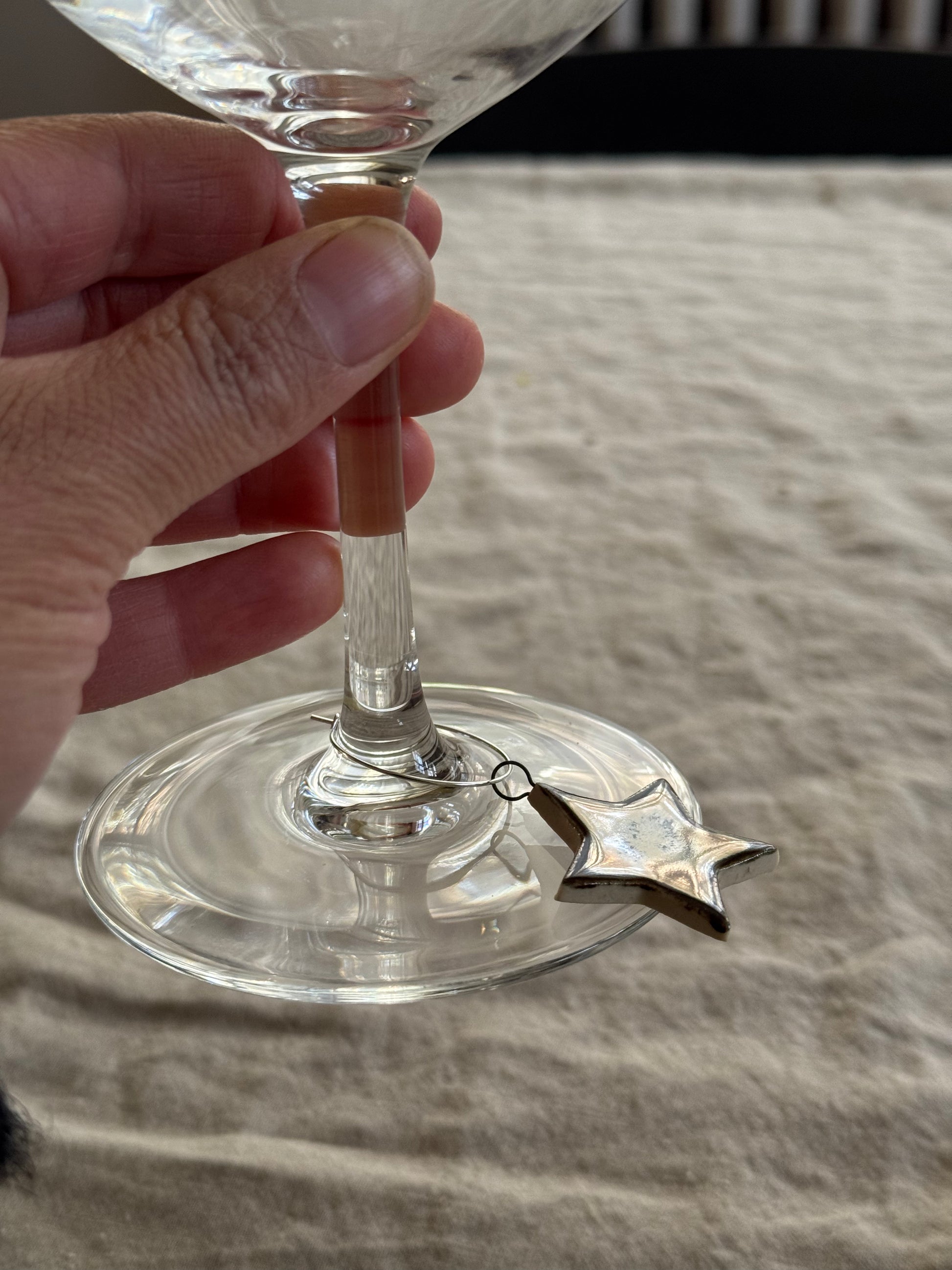 Clear glass with a star-shaped wine charm on a textured surface