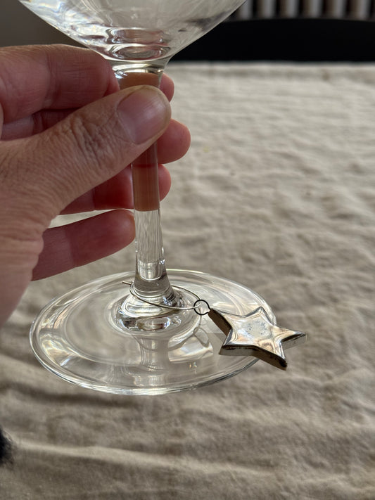 Clear glass with a star-shaped wine charm on a textured surface