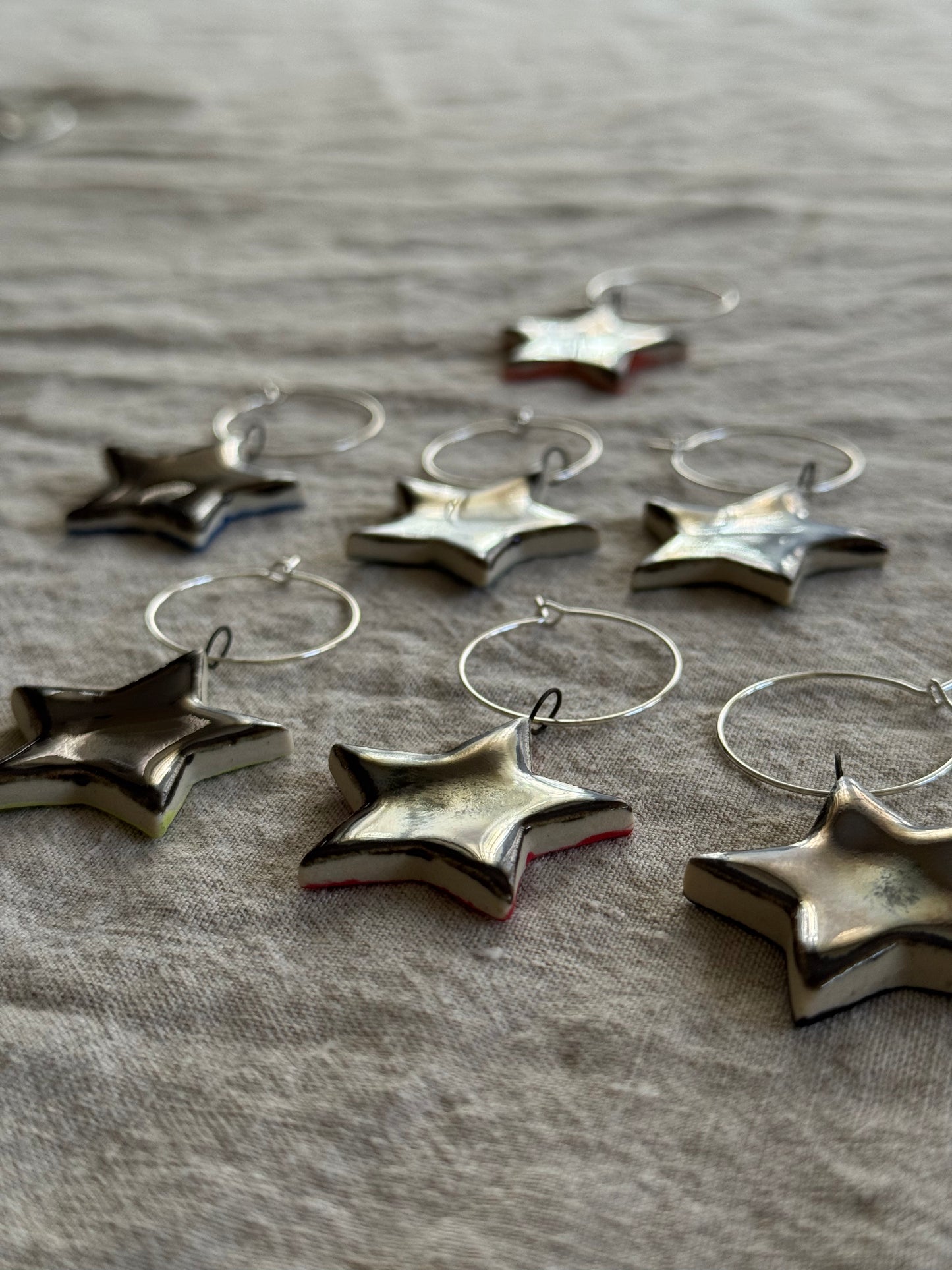 Silver star-shaped drink charms on a textured fabric background