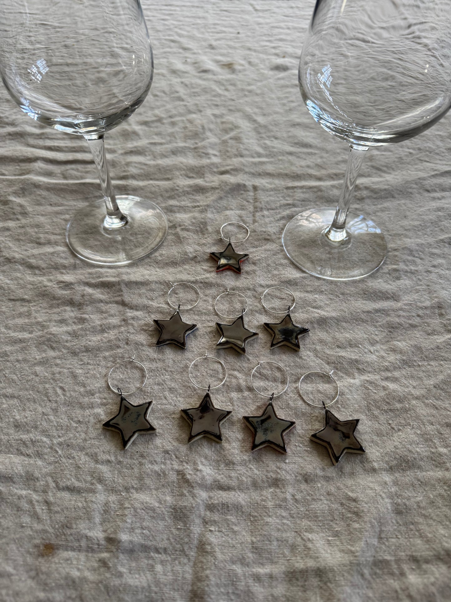 Star-shaped wine charms on a textured surface with two empty glasses.