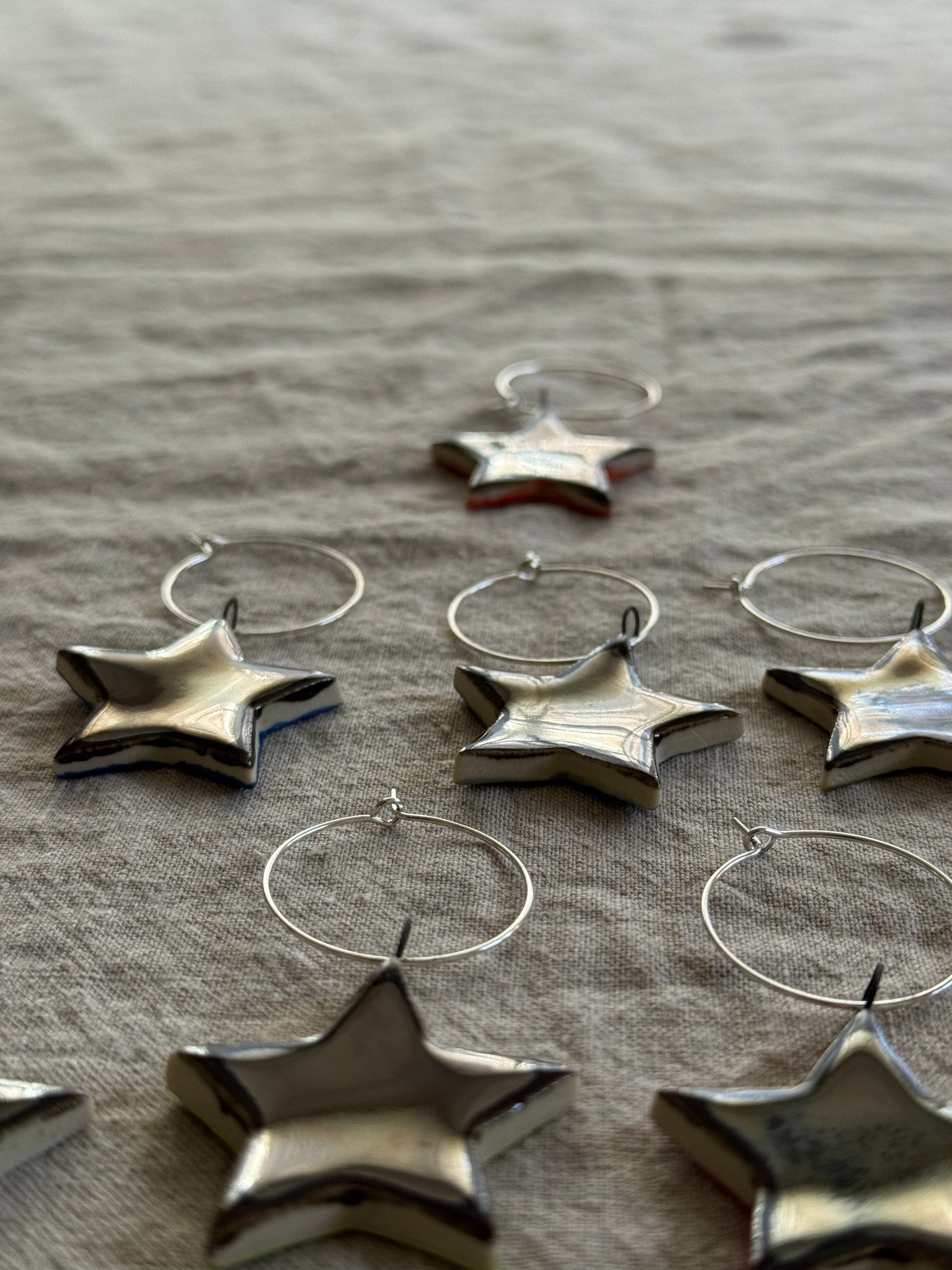 Silver star-shaped wine charms on a textured fabric background
